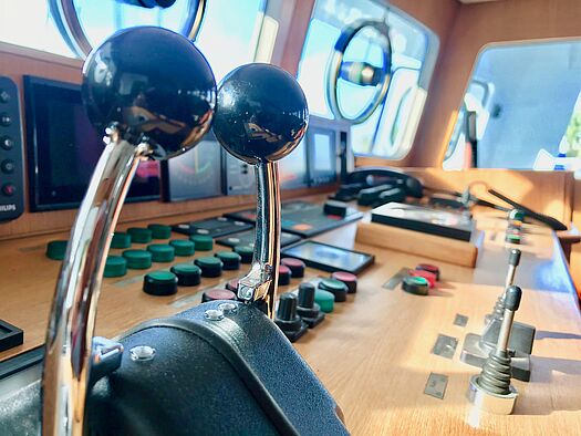 Bordelektronik der IBH für Fahrstand und Komfortsysteme auf dem Schiff Steuerpult mit Hebeln, Knöpfen in rot oder grün und einem Telefon
