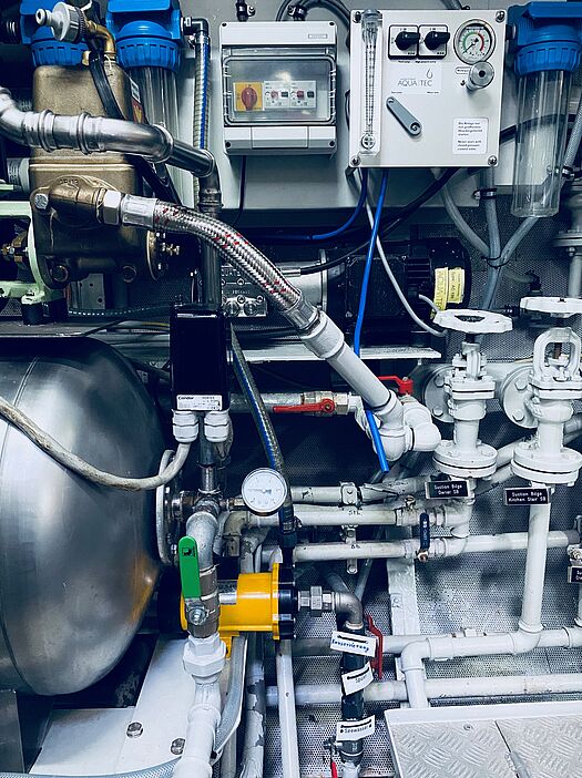 Technische Komfortsysteme für Yachten und Schiffe Silberner Tank mit Leitungen an einer Kontrollanlage mit Knöpfen und Schaltern
