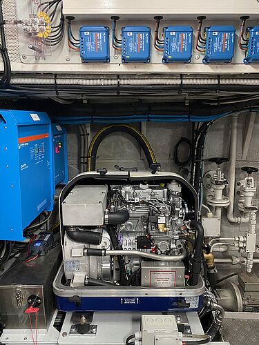 Bordnetzanlage der IBH für den Strom an Bord Grauer Motorblock mit zahlreichen Leitungen und mehreren blauen Kästen