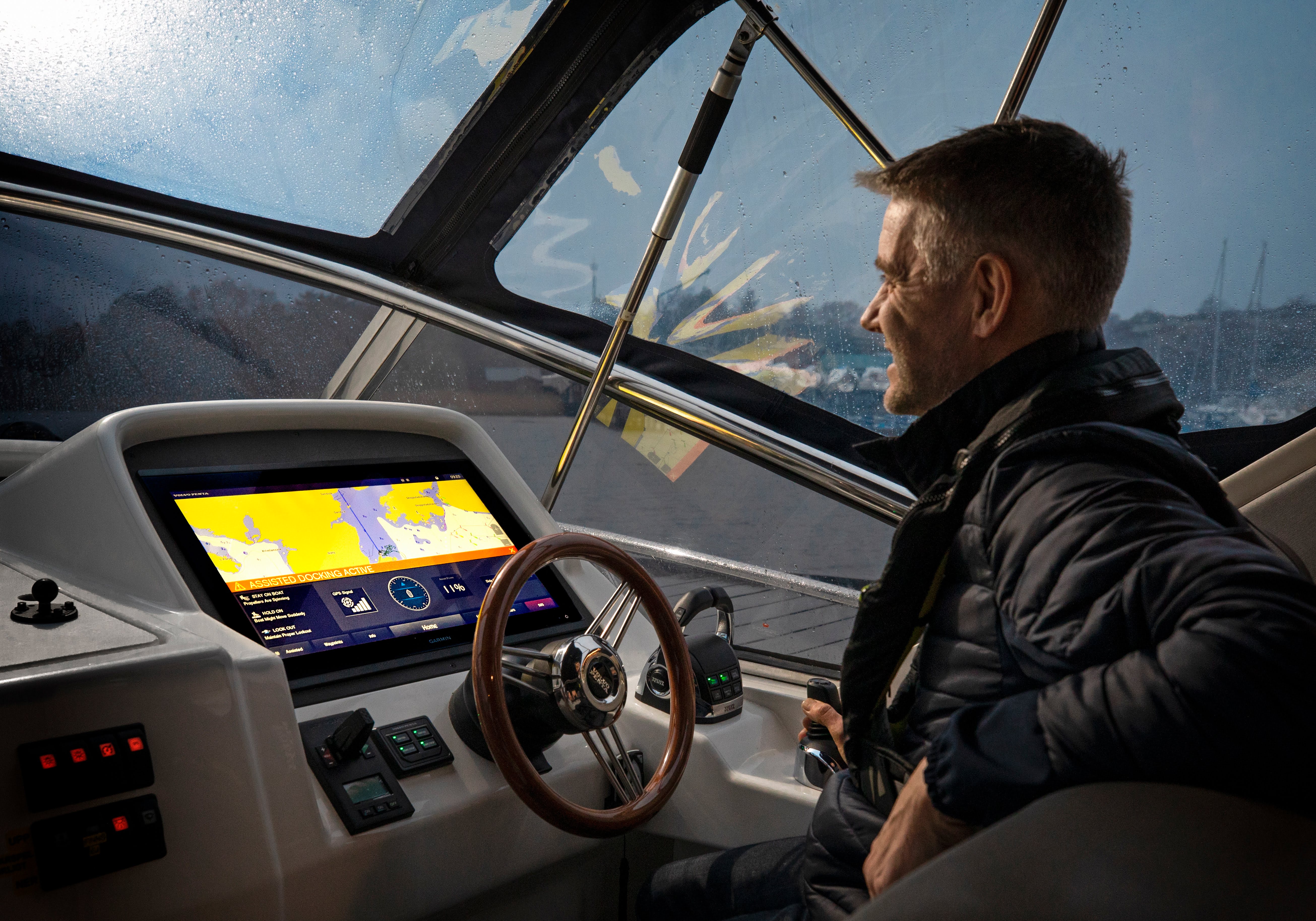 Mann am Steuer eines Bootes mit digitaler Seekarte auf einem Monitor