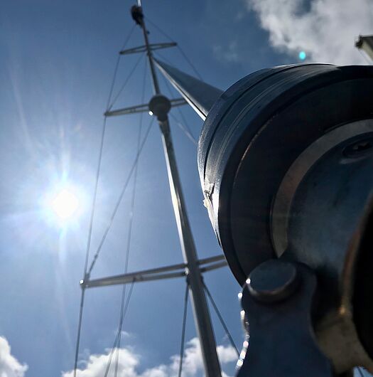 IBH Yachtservice für Tätigkeiten an Mast und Rigganlagen Schiffsmast mit zahlreichen Seilen vor blauem Himmel und Sonne